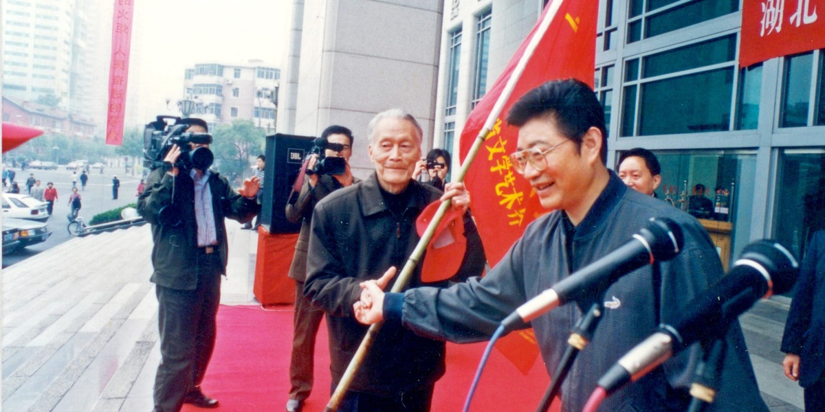 2002年5月，省文联赴延安采风团出发式上，省委常委、宣传部长繆合林（右一）向采风团代表、著名作家骆文（右二）授旗_fororder_2、2002年5月，省文联赴延安采风团出发式上，省委常委、宣传部长繆合林（右一）向采风团代表、著名作家骆文（右二）授旗 