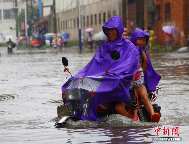 广西暴雨致街道积水过膝 民众涉水送子上学