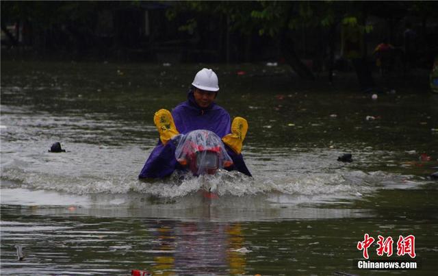 广西暴雨致街道积水过膝 民众涉水送子上学