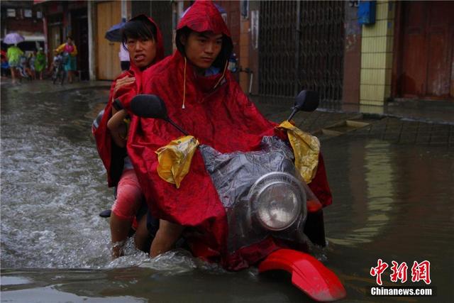 广西暴雨致街道积水过膝 民众涉水送子上学