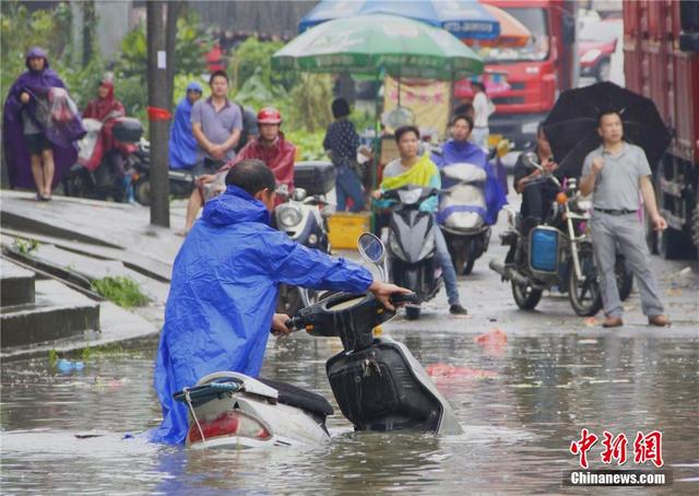 广西暴雨致街道积水过膝 民众涉水送子上学