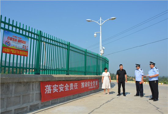 三门峡示范区阳店镇：“四强化”筑牢生命“防护堤”_fororder_阳店派出所民警查看“防溺水”警示牌  摄影   彭红勇