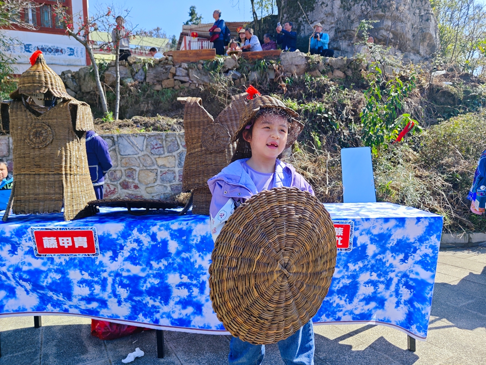 贵州安顺：万人欢度苗族跳花节_fororder_跳花节活动现场，小游客试穿阿歪寨藤甲  戴胜信 摄