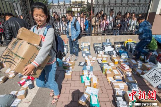 高校节后开学迎物流高峰 学生隔栅栏取快递