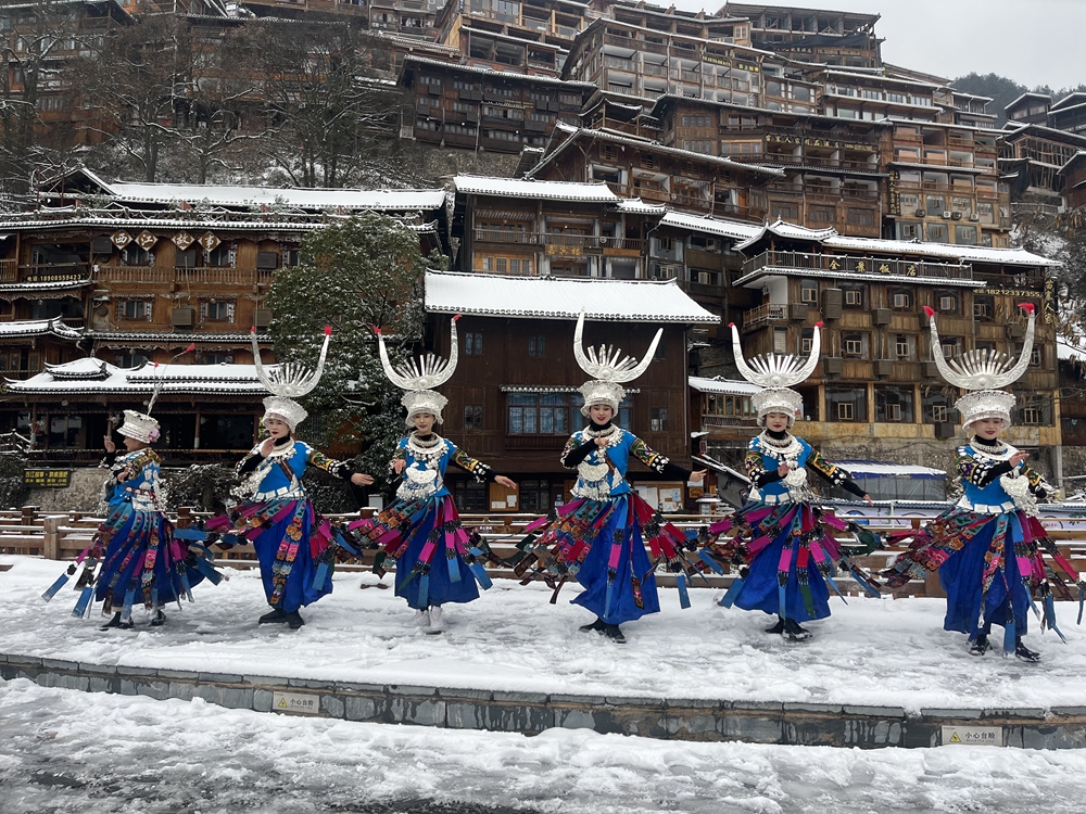 贵州雷山西江千户苗寨迎来降雪  冬日雪景如画_fororder_1月22日，贵州省雷山县西江千户苗寨迎来2024年第一场降雪。图为苗寨女孩在雪中翩翩起舞。