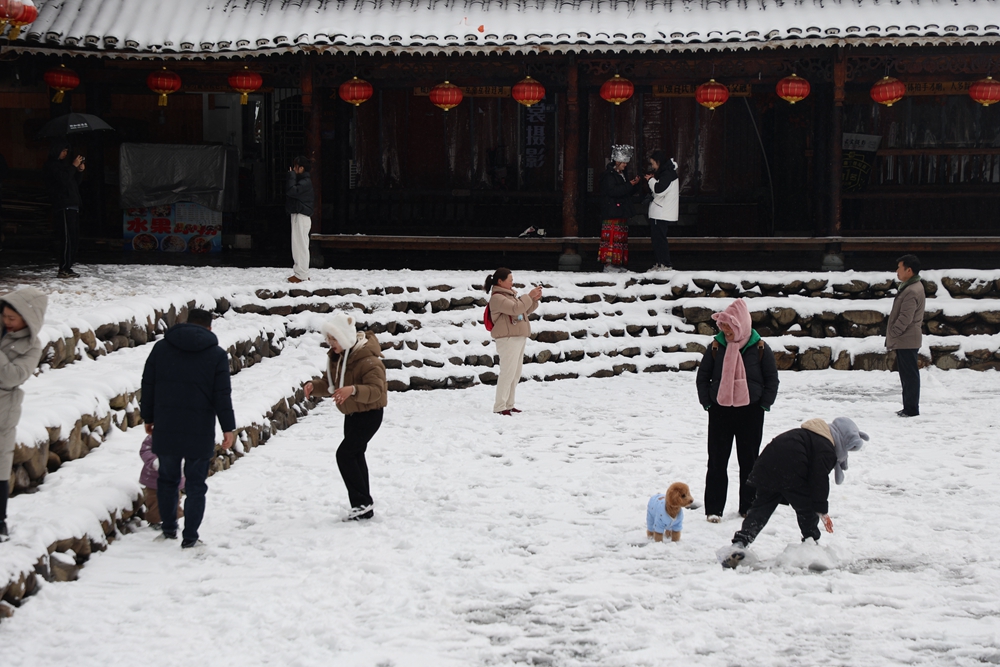 贵州雷山西江千户苗寨迎来降雪  冬日雪景如画_fororder_1月22日，贵州省雷山县西江千户苗寨迎来2024年第一场降雪。图为游客在玩雪。