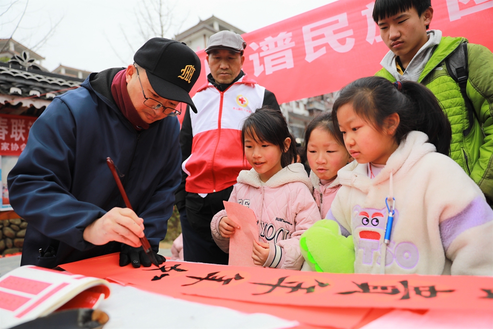 贵州雷山：写春联迎新春_fororder_2023年2月2日，在贵州省黔东南苗族侗族自治州雷山县龙头街道移民安置点，书法志愿者为居民义务写春联。