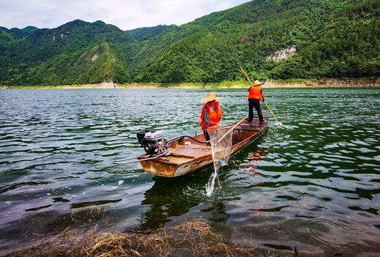 （供稿）贵州瓮安持续推进乌江流域水生态文明建设_fororder_瓮安县珠藏镇丰岩村村民卢锡永、冉戌英夫妇驾驶小船打捞江面垃圾（卢锡江 摄）