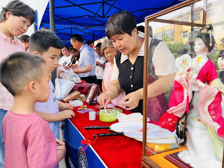 河北涞水：传承非遗技艺 促进文化振兴_fororder_图为非遗传承人正在向小朋友展示绢人的制作流程。（李金璐 摄）.JPG