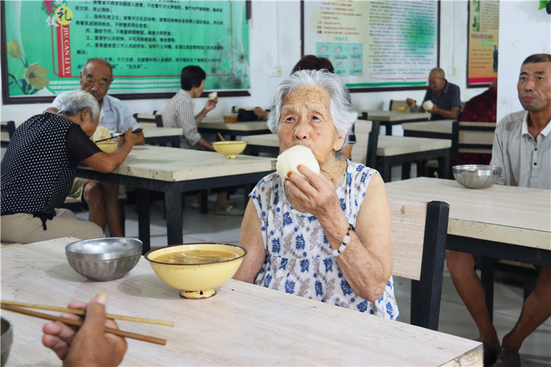 南阳市卧龙区：全力以赴做好汛情处置和排涝救援工作_fororder_被转移群众在陆营镇敬老院里吃午饭 摄影 王小军.JPG