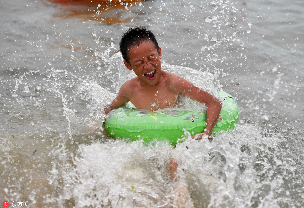 盛夏高温酷暑难耐 青岛浴场游客“下饺子”避暑